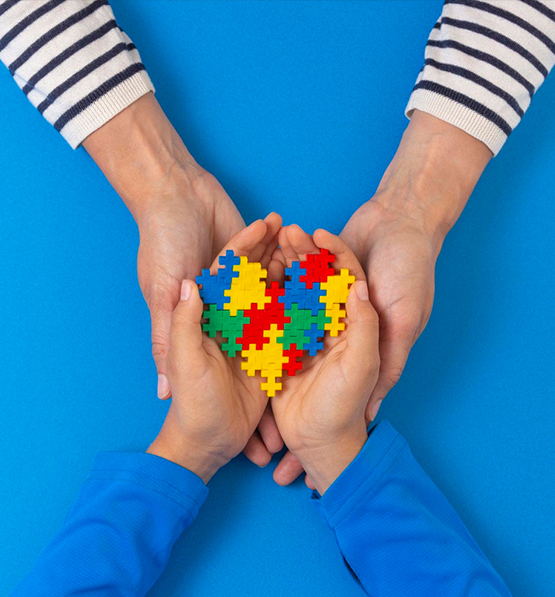 Two adults holding a child's hands over an autism awareness puzzle heart
